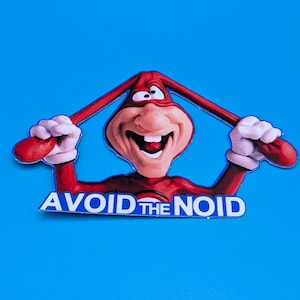 May include: A red cartoon character with a large smile and a red suit, holding two red sticks. The character is known as the Noid. The text "AVOID THE NOID" is printed in blue letters below the character.