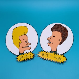 May include: Two cartoon characters, Beavis and Butt-Head, are depicted in profile on white circles with yellow starburst borders. Beavis has blonde hair and is on the left, while Butt-Head has brown hair and is on the right. The text "BEAVIS" and "BUTT-HEAD" is written in yellow on the starbursts.