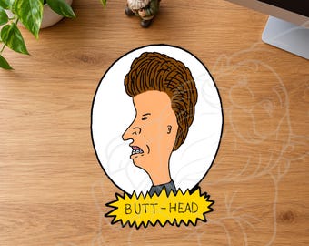 May include: A sticker featuring a cartoon illustration of the character Butt-Head in profile, shown with brown hair and a grey shirt inside a white oval. Below the oval is a yellow jagged speech bubble shape with the text BUTT-HEAD in black.