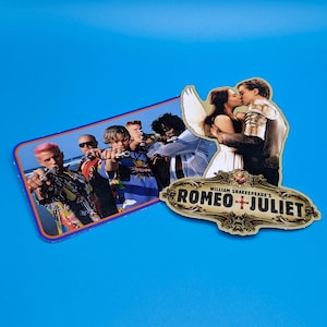 May include: A sticker featuring a scene from the film Romeo + Juliet, with a group of young men in the background and a couple kissing in the foreground. The sticker also includes the title "William Shakespeare's Romeo + Juliet" in a gold and red design.