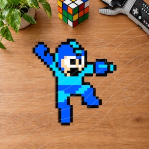 May include: A pixel art figure of the character Mega Man in a dynamic action pose. The figure is composed of various shades of blue, white, and black squares, depicting the character with one arm extended forward and the other raised upward.