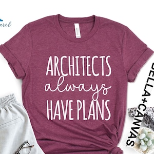 May include: A maroon t-shirt with the text "Architects always have plans" in white lettering.