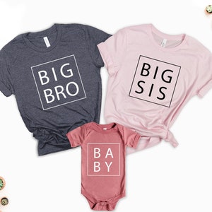 May include: Three shirts with the words "Big Bro", "Big Sis", and "Baby" in white text on a black background. The shirts are in different colors: dark grey, pink, and maroon.