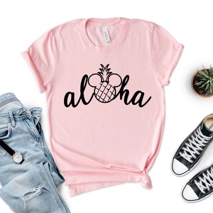 May include: Pink t-shirt with a black pineapple design and the word "Aloha" written in a cursive font. The pineapple has Mickey Mouse ears.