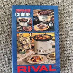 May include: A blue cookbook titled "Crock-Pot Slow Cooker Cuisine" with images of slow cookers and prepared dishes. The RIVAL brand name is prominently displayed at the bottom of the cover.
