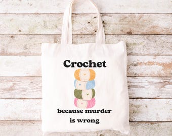 May include: A white tote bag with the text "Crochet because murder is wrong" and a stack of four colourful yarn balls.