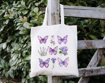 May include: A white tote bag with a purple floral design featuring butterflies and flowers. The bag has a long handle and is made of canvas.