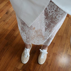 May include: White lace skirt with a white blazer and white sneakers.