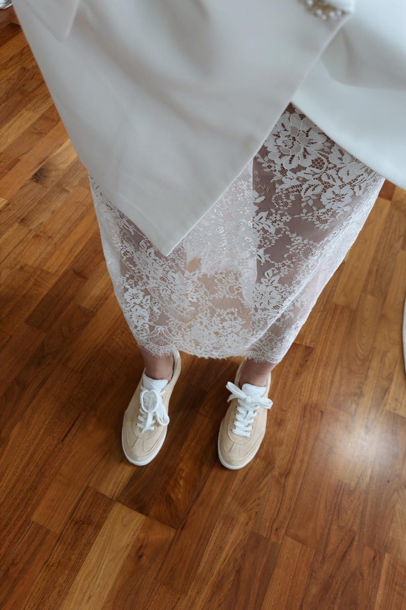 May include: White lace skirt with a white blazer and white sneakers.