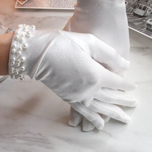 May include: A pair of white satin gloves with pearl embellishments at the wrist.