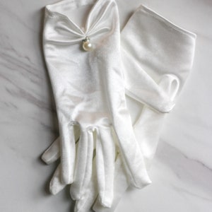 May include: A pair of white satin gloves with a pearl embellishment on the back of the hand.