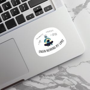 Puede incluir: Adhesivo blanco con el texto "ENGIN-NEARING MY LIMIT" y una ilustración de dibujos animados de una persona sentada con la cabeza entre las manos. El adhesivo también presenta ecuaciones y símbolos matemáticos.