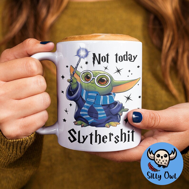 May include: White ceramic mug with a green baby Yoda character wearing a blue and white scarf and holding a magic wand. The mug has the text "Not today Slythershit" printed on it.
