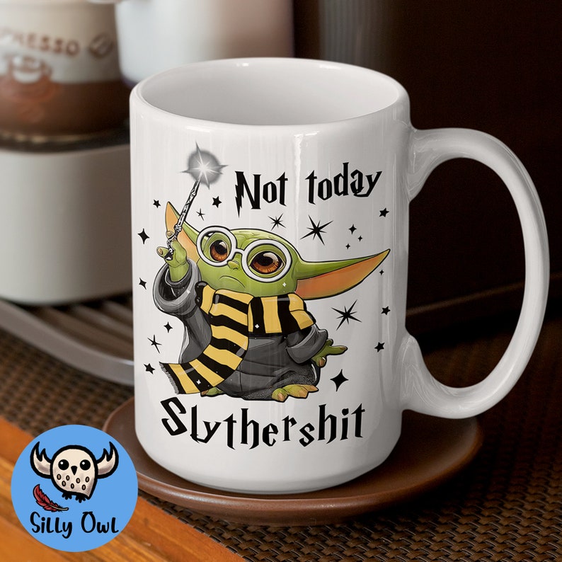 May include: White ceramic mug with a green and yellow cartoon character holding a wand. The mug has the text "Not today Slythershit" printed on it.