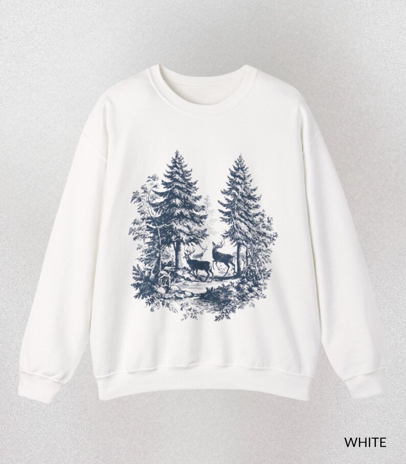 May include: White sweatshirt featuring a forest scene with two deer and tall trees in a dark blue print. The crew neck sweatshirt has long sleeves and the word "WHITE" is printed at the bottom.