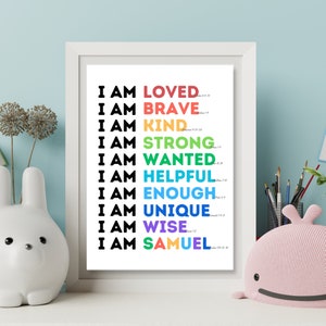 May include: A white framed print with a rainbow colored text design that reads "I am loved, I am brave, I am kind, I am strong, I am wanted, I am helpful, I am enough, I am unique, I am wise, I am Samuel".