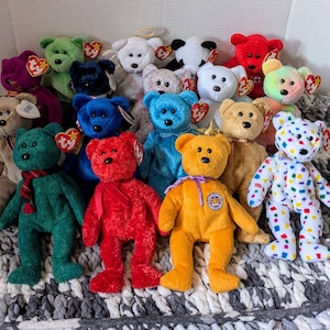 May include: A collection of colourful Beanie Babies, including a red, white and blue Beanie Baby with a Canadian flag patch, a green Beanie Baby with a red heart, and a yellow Beanie Baby with a crown.