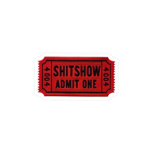 以下が含まれることがあります： 赤色のチケット型のステッカーで、黒色の文字で「SHITSHOW ADMIT ONE」と書かれています。 チケットの左右には垂直に「4004」の数字が印刷されています。 白い縁取りがあります。