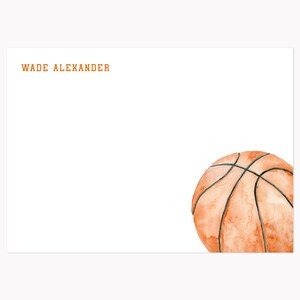 May include: White stationery with the name "WADE ALEXANDER" in orange lettering. A watercolor illustration of a basketball is in the lower right corner. The basketball is orange with black lines.