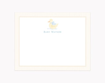 May include: A rectangular stationery card featuring a pale yellow duck illustration with a light blue ribbon around its neck. The text BABY WATSON is printed in blue below the duck. The card has a thin tan border and a vertical striped edge.