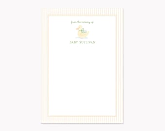 May include: A rectangular stationery card with a light beige vertical striped border and a thin gold frame. The center features a small yellow duck illustration with a green ribbon, the text "from the nursery of" and "BABY SULLIVAN".
