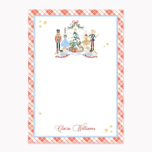May include: A rectangular stationery sheet featuring a red and white gingham border with a thin blue inner line. The top center displays a watercolor illustration of nutcrackers, ballerinas, and a Christmas tree. The name Clara Williams is printed in red.