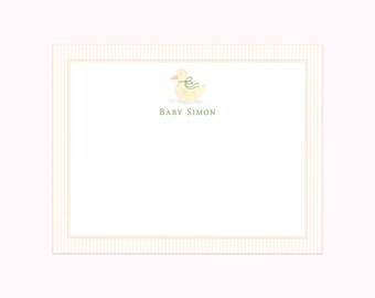 May include: A rectangular white card with a thin beige pinstripe border. Centered at the top is a watercolor illustration of a pale yellow duckling wearing a green ribbon around its neck. Below the duckling, the text BABY SIMON is printed in green.