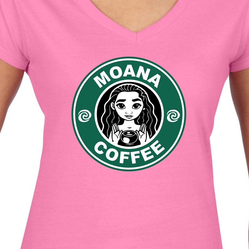 Puede incluir: Una camiseta rosa de cuello en V con un logotipo circular verde que presenta una imagen de dibujos animados de Moana sosteniendo una taza de caf&eacute;. El texto del logotipo dice "Moana Coffee" con un dise&ntilde;o de espiral a cada lado del texto.