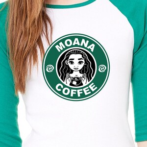 Puede incluir: Una camiseta de b&eacute;isbol blanca y verde con un logotipo circular verde que dice "Moana Coffee" con una imagen de dibujos animados de Moana sosteniendo una taza de caf&eacute; dentro del c&iacute;rculo.