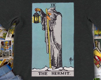 Może przedstawiać: Szary t-shirt w kolorze ciemnego hedera z vintage'ową ilustracją karty Pustelnika z talii tarota. Karta przedstawia mężczyznę w szacie z kapturem trzymającego latarnię i laskę, z tekstem "IX THE HERMIT" na dole.