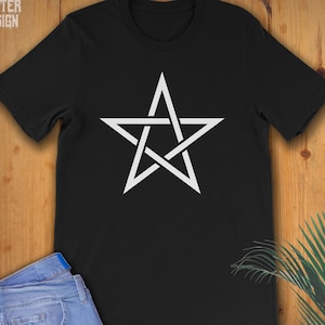 May include: A black t-shirt with a white pentagram design. The t-shirt is on a wooden surface.