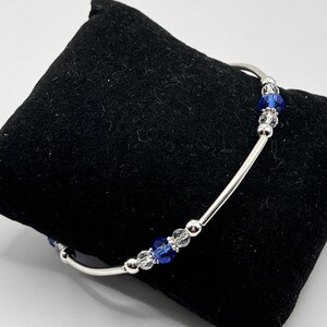 May include: A silver bracelet with blue and clear crystal beads.