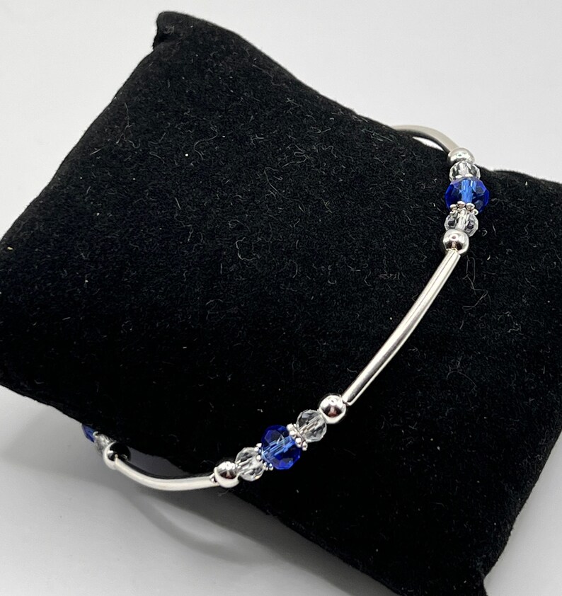 May include: A silver bracelet with blue and clear crystal beads.