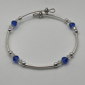 May include: A silver bangle bracelet with blue and clear crystal beads.