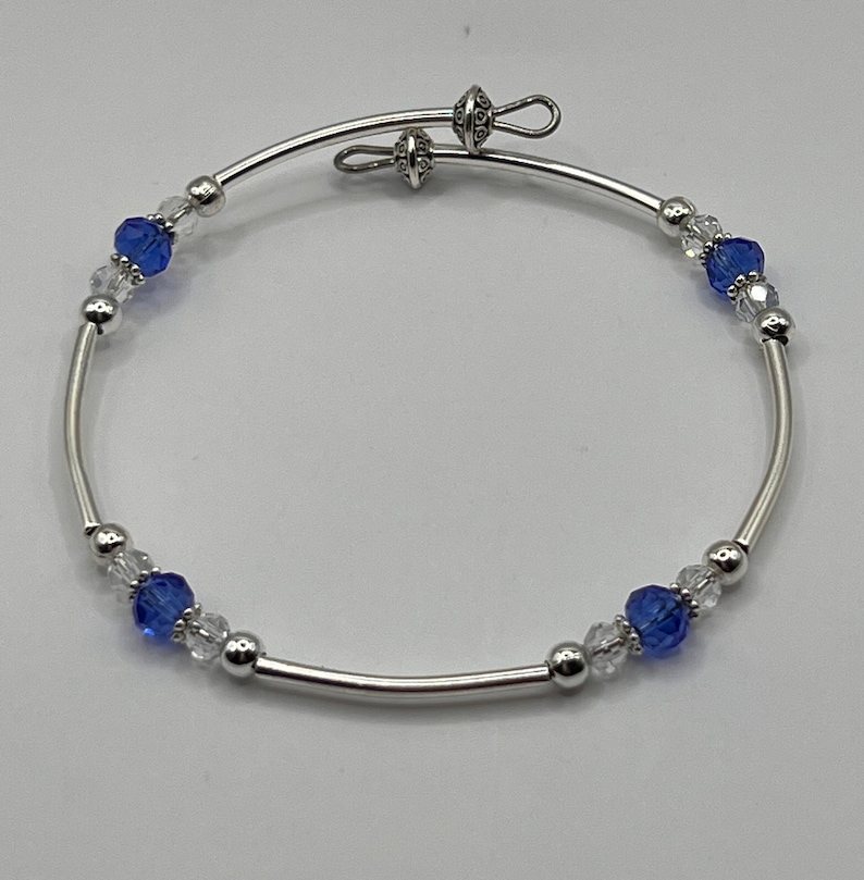 May include: A silver bangle bracelet with blue and clear crystal beads.