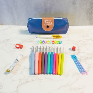 May include: A blue zippered pouch with the text "Yarn Stitch" on it, along with a set of colorful crochet hooks, stitch markers, a measuring tape, and a needle threader.