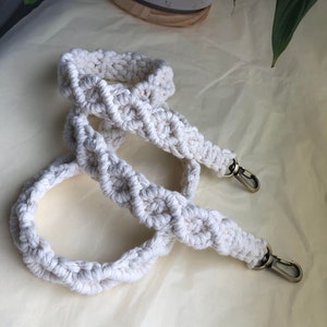 May include: Two white cotton macrame straps with gold metal clasps. The straps are woven in a diamond pattern.