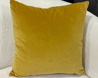 May include: A mustard yellow velvet pillow on a white couch.