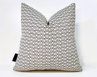 Könnte beinhalten: Ein weißes Kissen mit einem schwarzen geometrischen Muster. Das Kissen ist quadratisch und hat ein schlichtes Design.