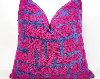 May include: A magenta decorative pillow with a geometric pattern in a darker shade of purple. The pillow has a textured, woven appearance and is square-shaped.