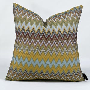 Może przedstawiać: Dekoracyjna poduszka z wzorem chevron w odcieniach żółtego, zielonego, niebieskiego i czerwonego.