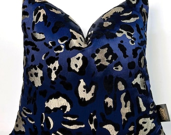 May include: A navy blue throw pillow with a black and gold leopard print pattern. The pillow has a subtle sheen and a soft, plush texture. The pillow is decorated with a small, gold tag that reads "Mood Home".