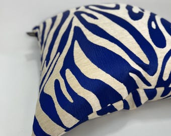 May include: A square throw pillow featuring a bold, high-contrast pattern of deep blue organic, flowing shapes set against a textured, off-white fabric background. The design covers the entire visible surface of the pillow, creating a striking visual.