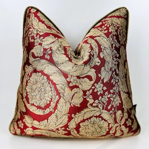 Peut inclure: Un coussin décoratif rouge et or avec un motif floral.