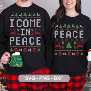 Könnte beinhalten: Schwarze Sweatshirts mit den Wörtern "I COME IN PEACE" und "PEACE" in Weiß, mit einem festlichen Muster aus Rentieren, Weihnachtsbäumen und Geschenken in Rot und Grün. Die Personen tragen rot-schwarz karierte Schlafanzughosen.