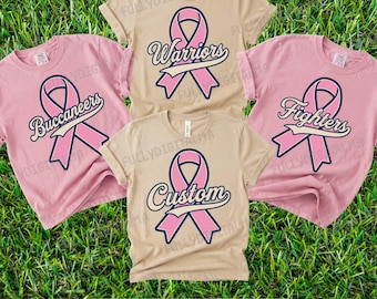 May include: Four short-sleeve t-shirts in light pink and beige colors. Each shirt features a pink awareness ribbon graphic with a dark blue outline. The text "Warriors," "Buccaneers," "Fighters," and "Custom" is printed across the ribbons.