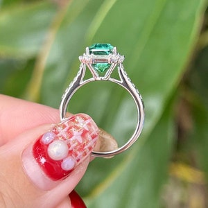 Pu&ograve; includere: Un anello d'argento con un grande smeraldo verde circondato da diamanti pi&ugrave; piccoli. L'anello &egrave; incastonato in stile halo.