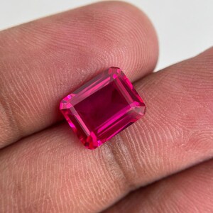 May include: A vibrant pink emerald cut gemstone with a high polish.