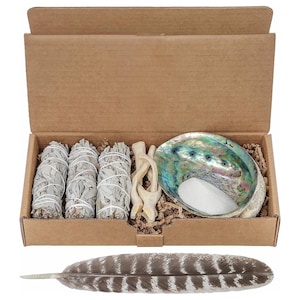 Peut inclure: Un coffret de purification dans une boîte en carton. Le coffret comprend trois fagots de sauge blanche, un petit coquillage d'ormeau avec du sable blanc, un morceau de bois flotté et une plume brune et blanche.