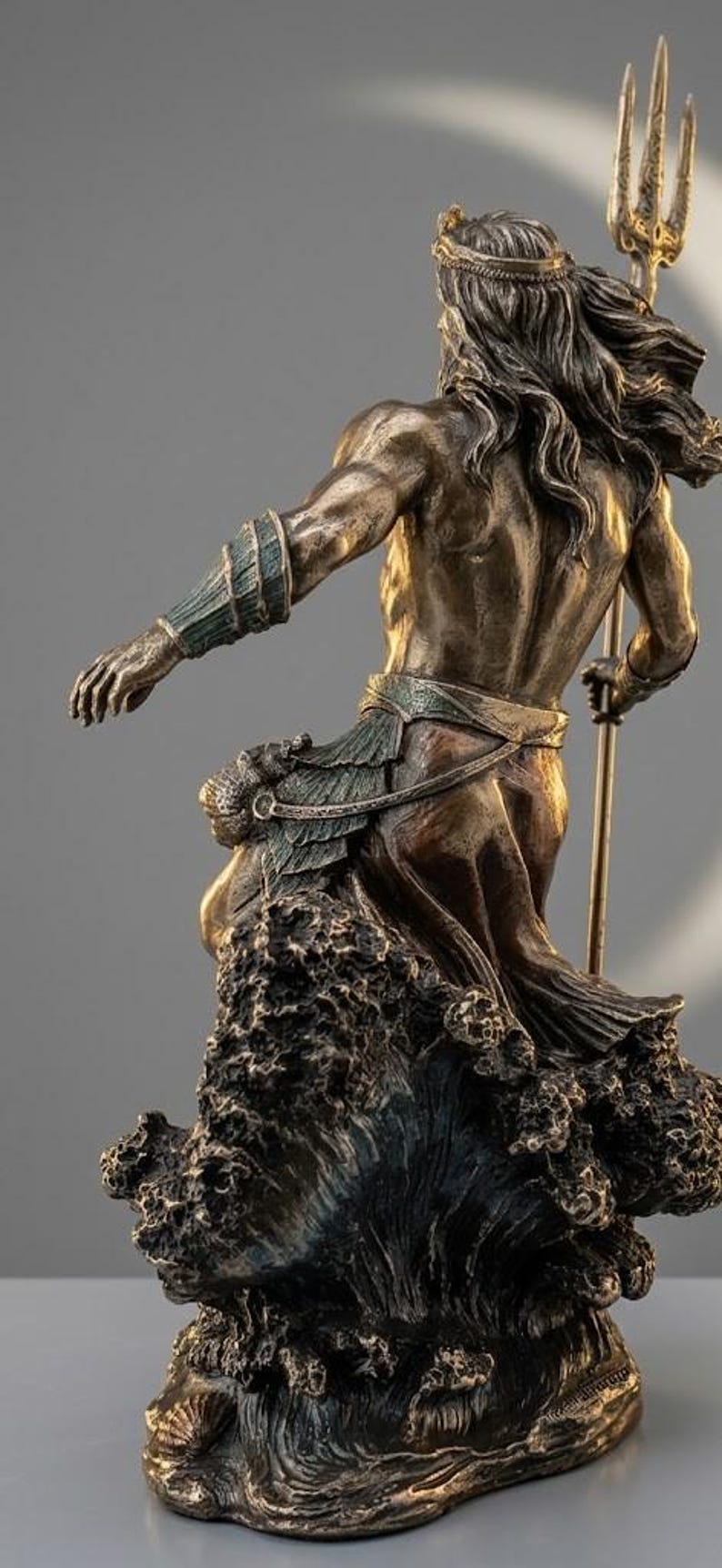 May include: Bronze statue of a muscular figure, possibly a god, with long hair and a crown, holding a trident. The figure is emerging from stylized waves. The statue has a detailed, aged appearance.